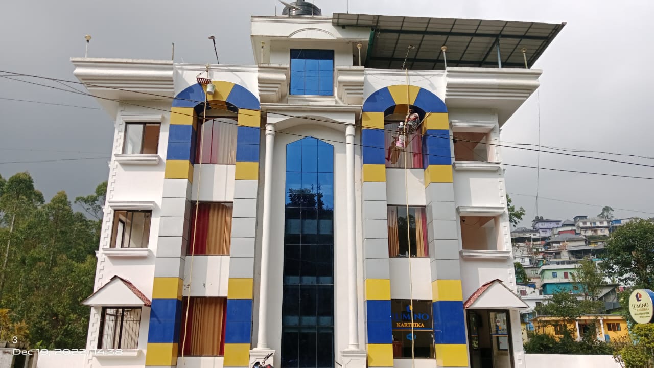 Outside view of the blue and yellow Lumino Karthika building in Munnar